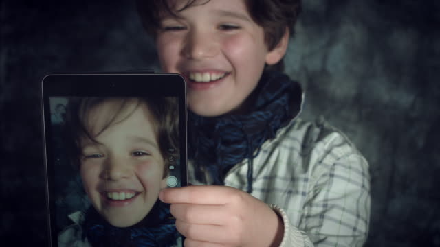 4K-tiro-alta-tecnología-de-un-niño-haciendo-un-Selfie-en-su-Tablet-y-ríe