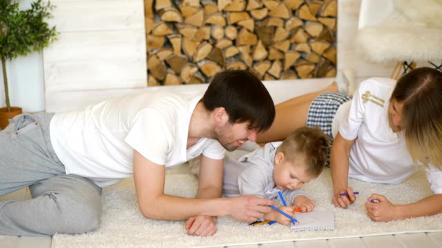 Vater-Mann-Mutter-hilft-ihrem-Kind-bildneren-Inihrem-Wohnzimmer