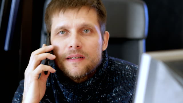 Hombre-usando-computadora-y-hablando-por-teléfono-celular.