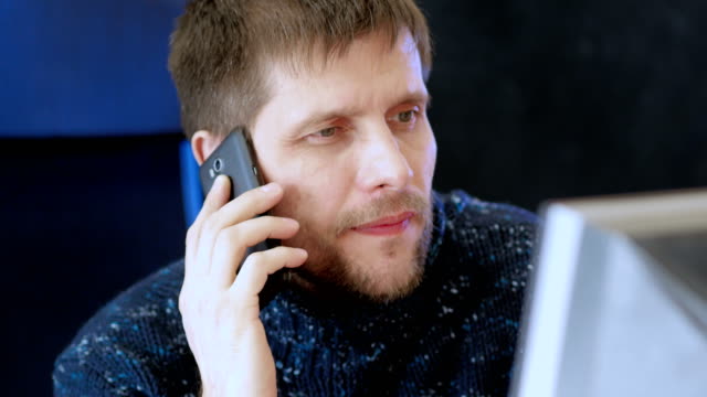 Hombre-usando-computadora-y-hablando-por-teléfono-celular.