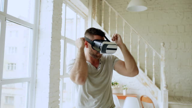 Fröhlichen-jungen-Mann-tanzen,-während-erste-Erfahrungen-im-Umgang-mit-360-VR-Kopfhörer-Brille-der-virtuellen-Realität-im-Schlafzimmer-zu-Hause