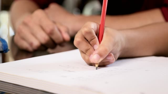 Nahaufnahme-des-jungen-Mädchens-Hand-schreiben-Bleistift-auf-Schulheft