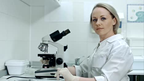Hübsche-Frau-mit-Blick-in-die-Kamera-im-Labor-Mikroskop