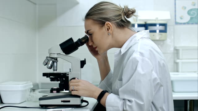 Mujer-sorprendida-trabajando-con-un-microscopio-en-el-laboratorio
