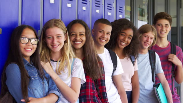 Teenager-Schulkinder-lächelnd-zu-Kamera-im-Flur-der-Schule