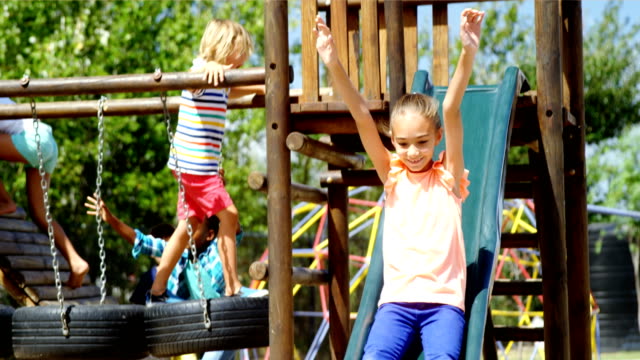 Happy-schoolgirl-playing-on-slide-in-playground