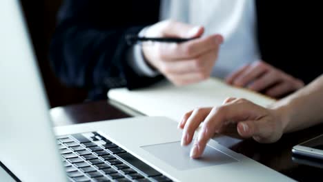 Hands-of-man-write-and-woman-work-at-pc-at-desk