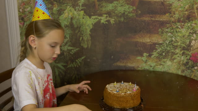 Das-Mädchen-entfernt-die-Kerzen-aus-dem-Kuchen.-Das-Mädchen-zieht-Kerzen-aus-dem-Kuchen-stand-auf-dem-Tisch.