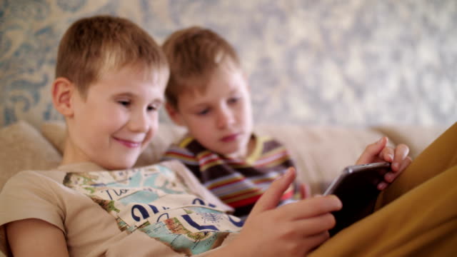 Kinder-spielen-auf-dem-Tablet-im-Hause-auf-der-Couch-sitzen