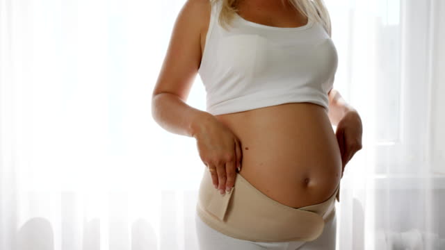 werdende-Mutter-strafft-die-Mutterschaft-Gürtel-und-berührt-den-großen-Bauch-in-Zeitlupe