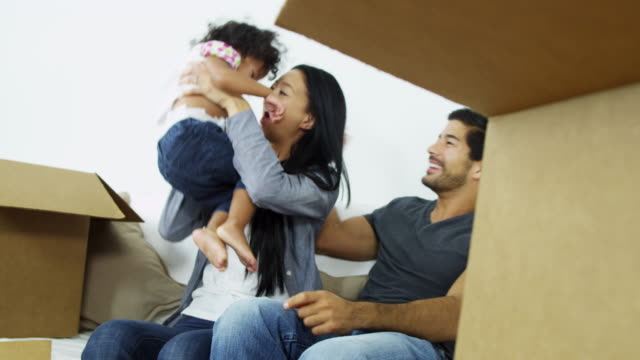 Ethnische-Eltern-spielen-Baby-Mädchen-im-neuen-Zuhause
