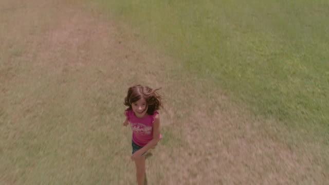 Junges-Mädchen-Kind-läuft-im-grünen-Feld-jagen-Drohne-Kamera