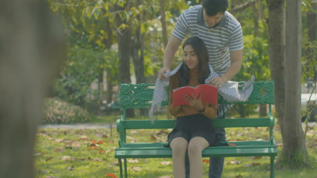 Happy-young-couple-relaxing-in-the-park-on-a-bench,-love-concept.