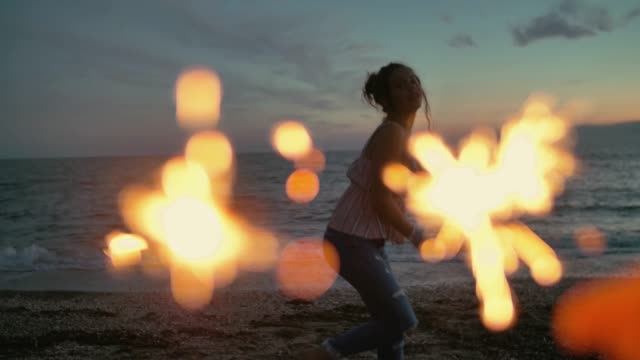 teenager-girl-with-sparklers-dancing-on-the-beach.-shot-in-slow-motion