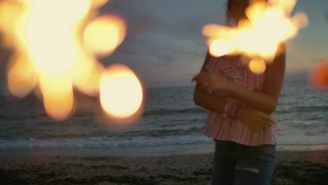 teenager-girl-with-sparklers-dancing-on-the-beach.-shot-in-slow-motion