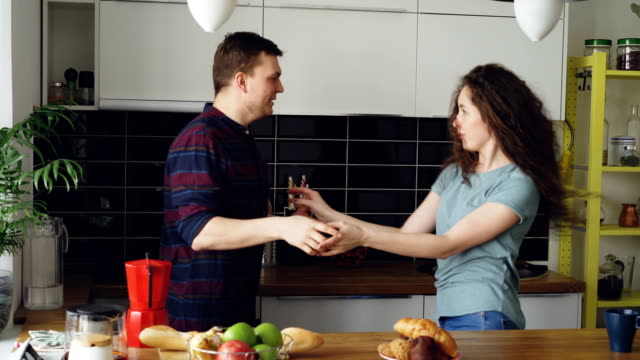 Attractive-young-joyful-couple-have-fun-dancing-while-cooking-in-the-kitchen-at-home