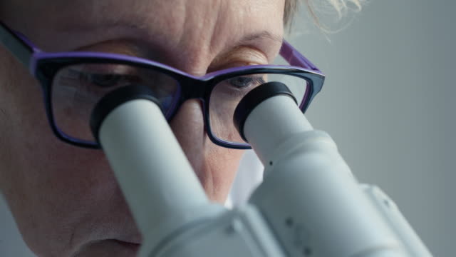 Mujer-mirando-a-través-de-un-microscopio-científico