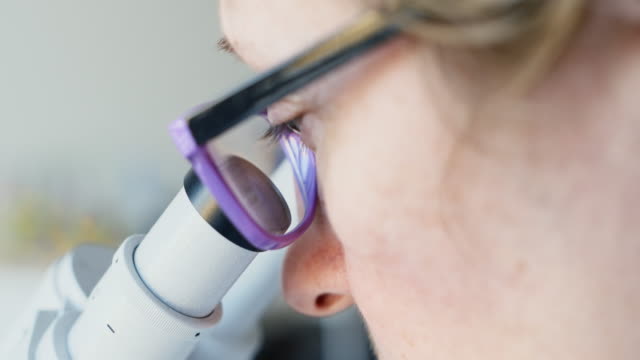 Mujer-mirando-a-través-de-un-microscopio-científico