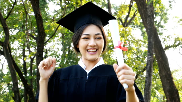 Jóvenes-estudiantes-mujer-Asia-usando-graduación-sombrero-y-vestido,-fondo-del-jardín,-mujer-con-el-concepto-de-graduación.