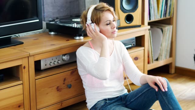 woman-sits-next-to-the-turntable-and-listens-to-music