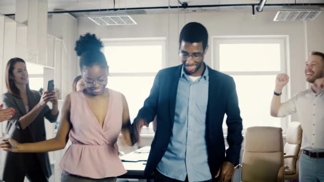 Americanos-africano-trabajadores-masculinos-y-femeninos-haciendo-graciosos-pasos-de-baile-étnico-en-fiesta-de-oficina-con-colegas-multiétnicos-4K