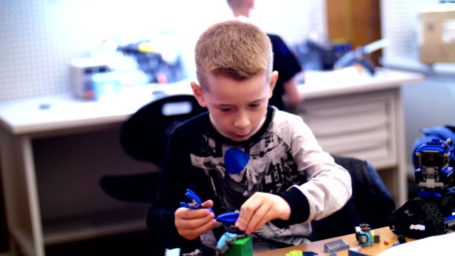el-niño-de-10-años,-juega-en-el-diseñador-de-cubos,-placas,-circuitos,-cables.-un-pequeño-inventor-crea-robots,-máquinas-de-diferentes-partes-del-diseñador