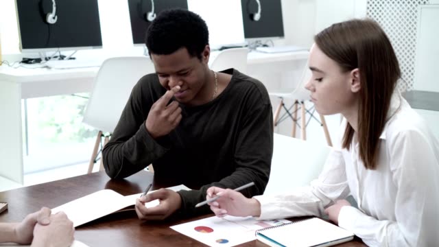 Group-of-diverse-economics-students-making-project-together.-Caucasian-girl-and-African-guy-sharing-ideas-and-taking-notes-at-team-meeting