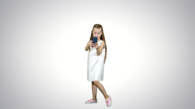 Glückliches-kleine-Mädchen-nehmen-ein-Selbstporträt-mit-einem-Smartphone-auf-weißem-Hintergrund