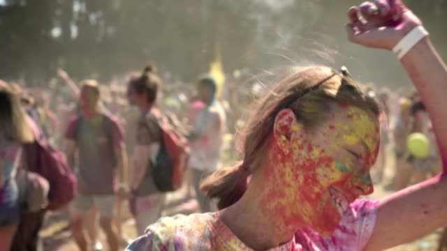 Young-lively-girl-in-colourful-powder-is-jumping-and-dancing-on-holi-festival-in-daytime-in-summer,-color-concept,-emotional-concept