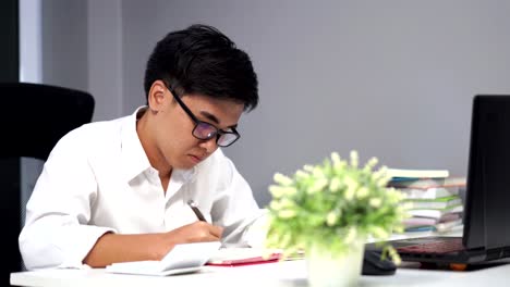 junger-Mann-studieren-und-Schreiben-auf-Notebook-mit-Laptop-computer