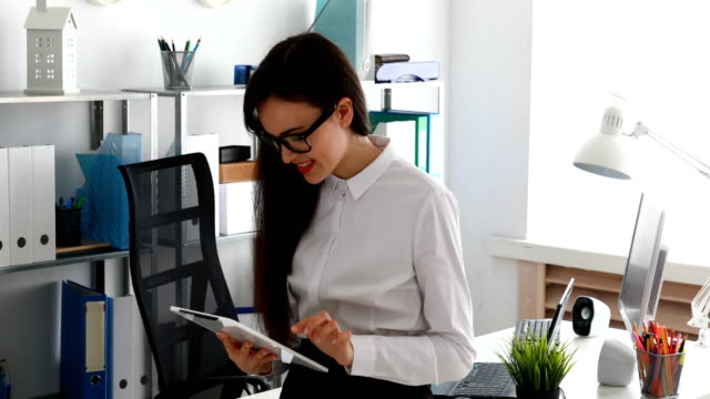 businesswoman-using-tablet-and-smiling-in-modern-office