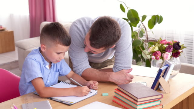 Padre-hijo-de-enseñanza-para-escribir-letras-en-el-cuaderno