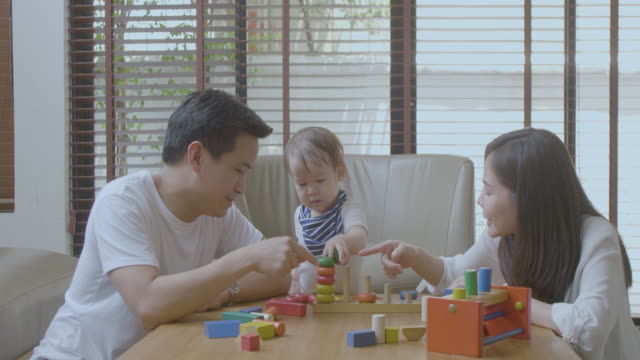 Glückliche-Mutter,-Vater-und-kleinen-asiatischen-jungen-spielen-mit-Holzspielzeug-Blöcke-zu-Hause