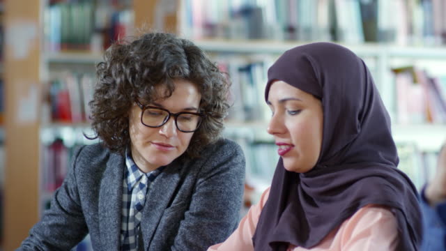 Frau-in-Hijab-arbeiten-mit-Lehrerin-bei-Lektion