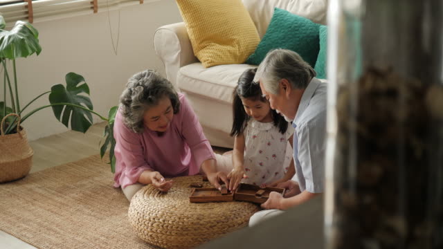 Asiatische-älteres-Paar-spielen-zusammen-mit-einem-kleinen-Mädchen-zu-Hause.-Familie-Senior-Lifestyle-Konzept.