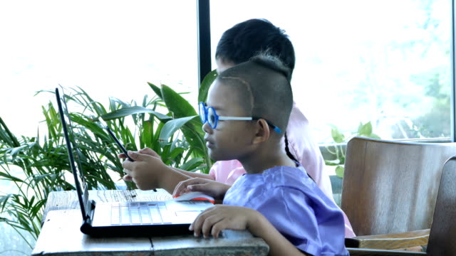 Feliz-muchacho-asiático-dos-personitas-con-ordenador-portátil.
