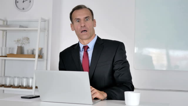 Shocked-Middle-Aged-Businessman-Wondering-while-Looking-at-Camera