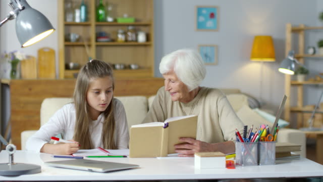 Großmutter-helfen-Mädchen-bei-den-Hausaufgaben
