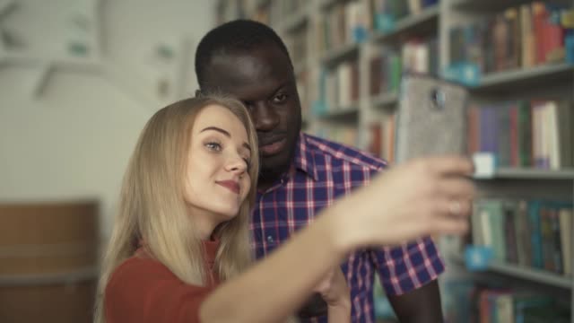 Afrikanische-Amerikaner-und-europäische-Dame-nehmen-Selfie-in-der-Bibliothek