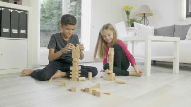 zwei-junge-glückliche-Kinder-Bruder-und-Schwester-zusammen-Spaß-zu-Hause-mit-einem-hölzernen-Backstein-Spielzeug-Spiel