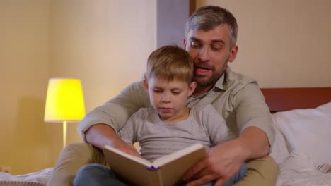 Vater-lesen-Märchen-und-umarmt-Sohn-auf-Bett