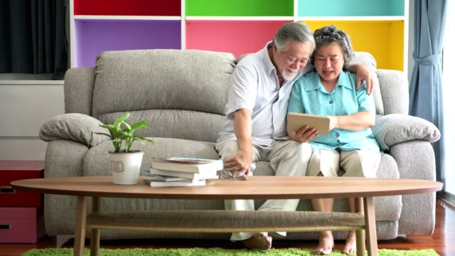 Senior-pareja-sentada-y-mirando-tablet-en-sala-de-estar.