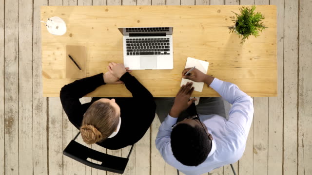 Dos-empresarios-sentados-juntos-trabajando-en-un-escritorio-de-oficina-poniendo-notas-al-cuaderno
