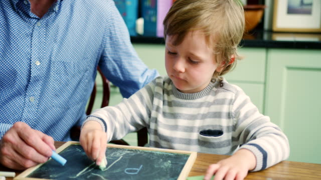 Father-Teaching-Son-To-Write-Using-Chalk-And-Blackboard