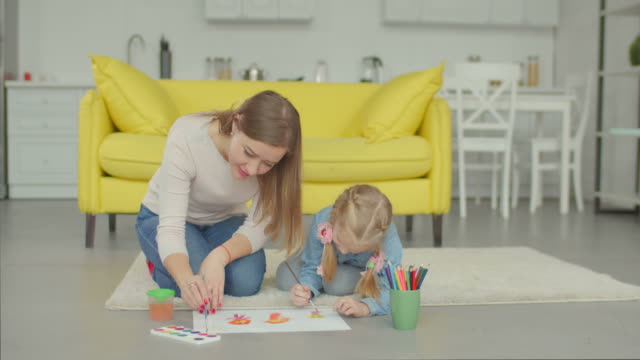 Cute-girl-with-mother-making-painting-at-home