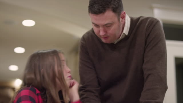 Ein-Vater-seine-Tochter-mit-ihren-Hausaufgaben-in-der-Küche-zu-helfen