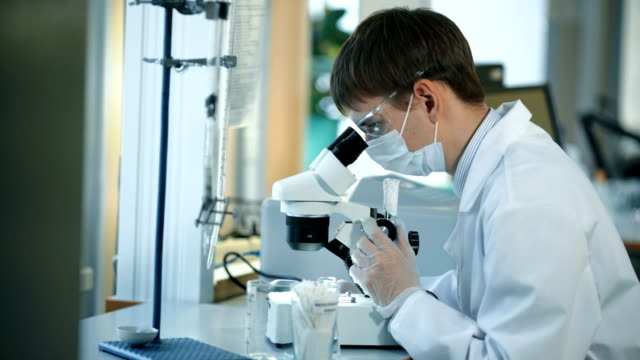 Científico-de-la-buscando-un-través-de-un-microscopio-en-un-laboratorio