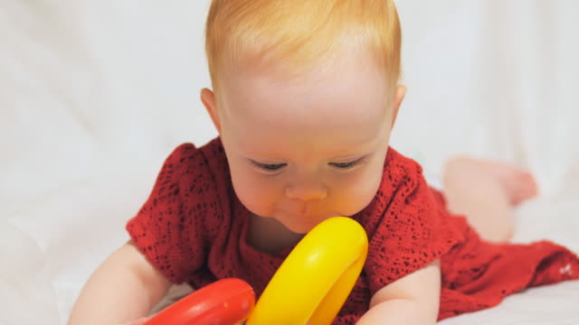 Kleines-Baby-in-einem-roten-Kleid-mit-Spielzeug-spielen