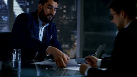 Late-at-Night-Businessman-Businessman-Has-Conversation-with-Important-Client,-They-Come-to-an-Agreement,-Both-Sign-Contract.-In-the-Background-Big-City-Window-View.