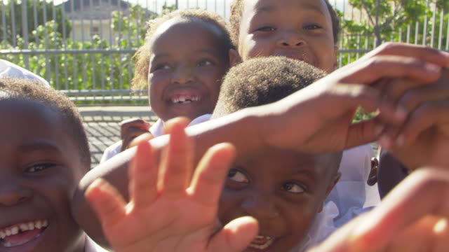 Young-school-kids-in-playground-wave-to-camera,-slow-motion